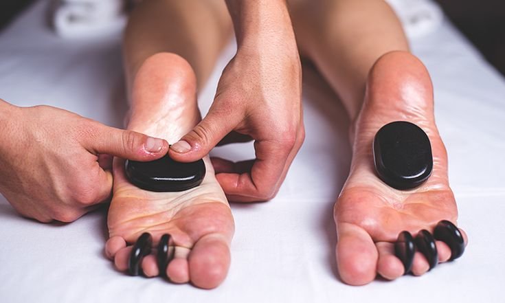 Photo of feet being massaged with hot stones on top of them