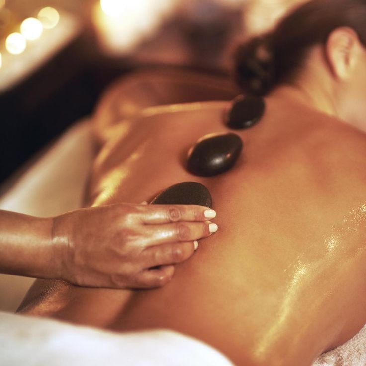 Picture of woman receiving a back massage with hot stones on top